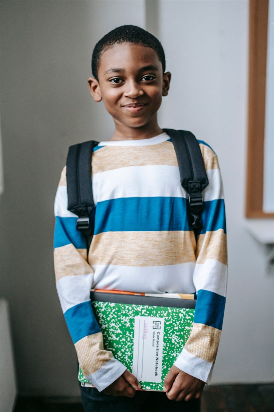A young author holding his notebook and books, smiling to camera
