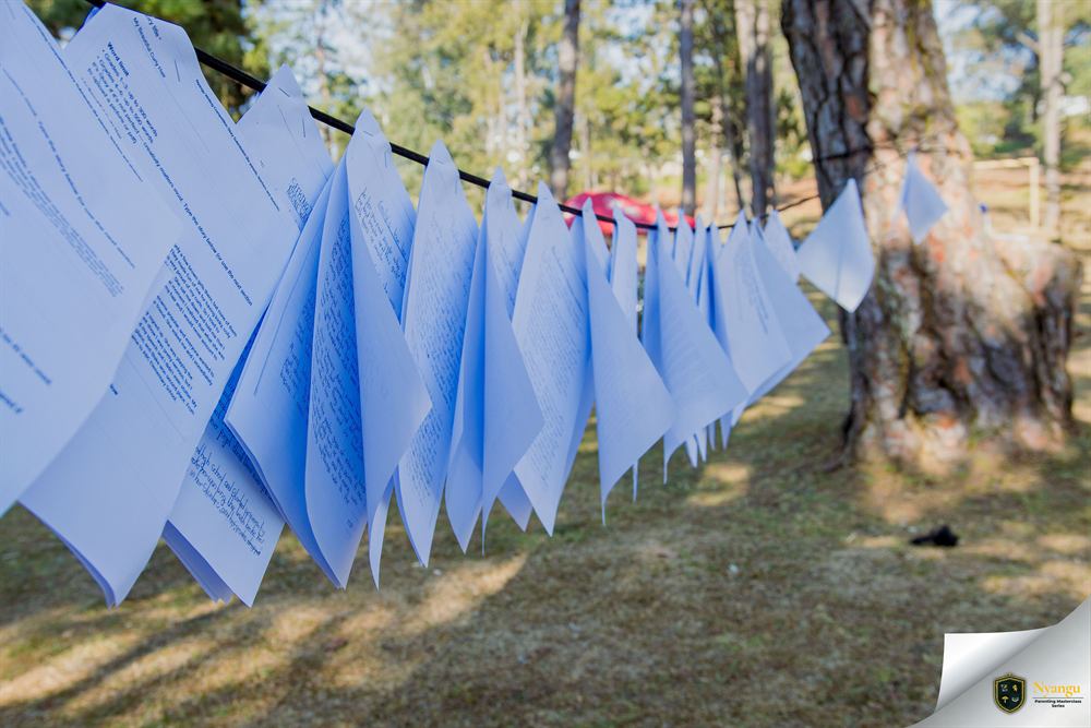 Children's handwritten stories pegged along a line between the trees
