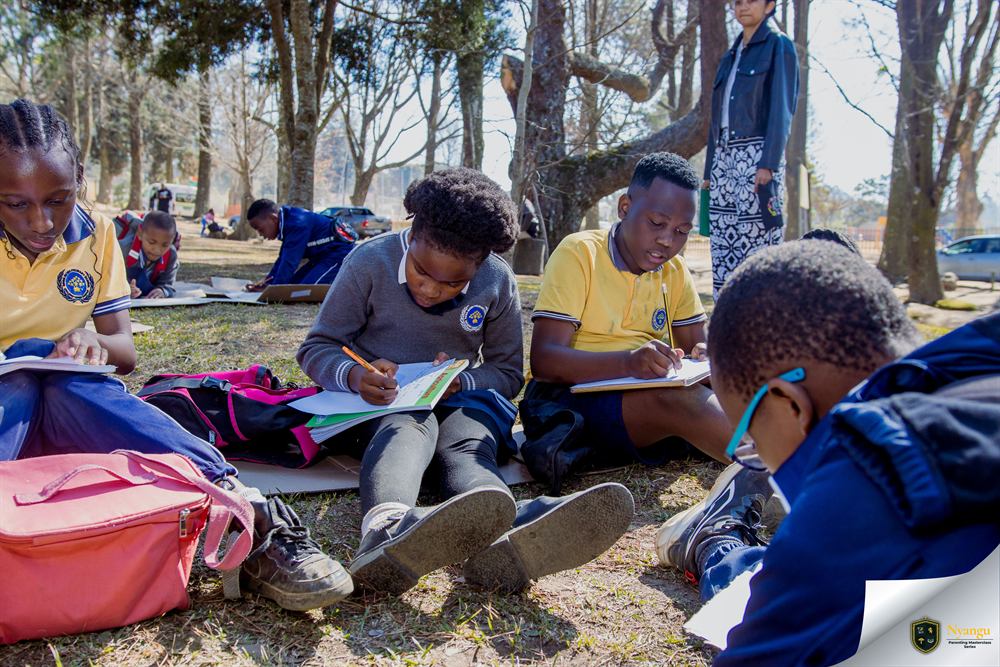 Children writing their stories on the grass at Coronation Park